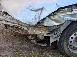 A wrecked car parked on the side of a city road photo