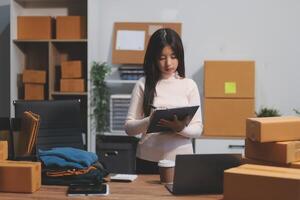A woman is using a tablet while standing in front of boxes photo