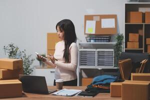 A woman standing in front of a desk with boxes and a laptop photo