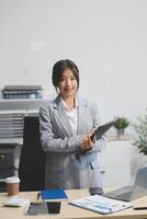 Asian businesswoman standing at desk with laptop photo