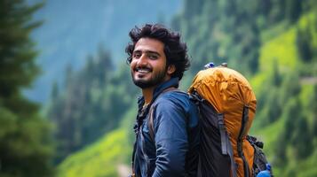 A man with a backpack smiles while standing in the mountains photo