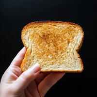 A person holding a piece of toast in their hand photo