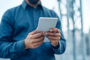 Man using smartphone outdoors while standing near telecommunications tower in bright daylight photo
