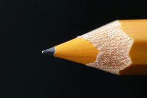 Close-up of a sharpened yellow pencil against a dark background emphasizing its fine tip and texture photo