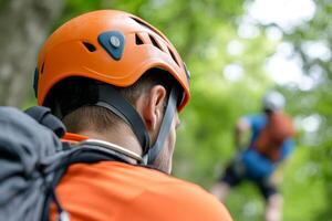 Person wearing an orange helmet preparing for an outdoor climbing activity in a lush green forest setting photo