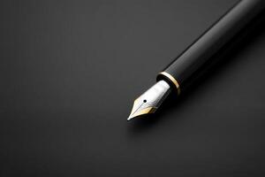 Elegant black fountain pen with a golden nib placed on a dark background in a minimalistic setting photo