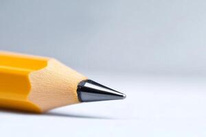 Close-up of a sharpened yellow pencil on a white surface showcasing its fine tip and texture photo
