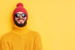 Young man smiles while wearing a bright yellow sweater and hat against a vibrant yellow background in a cheerful setting photo