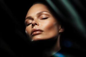 Model showcasing serene beauty with closed eyes and illuminated skin in a dark setting surrounded by light patterns photo