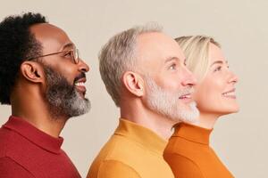 Diverse group of three individuals smiling and looking upward against a neutral background in a studio setting photo