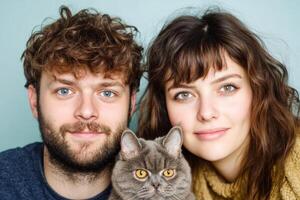 Couple poses with their gray cat in a cozy indoor setting with soft lighting and cheerful expressions photo