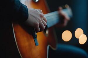 Hands playing an acoustic guitar amidst softly glowing candles in a warm ambiance setting photo