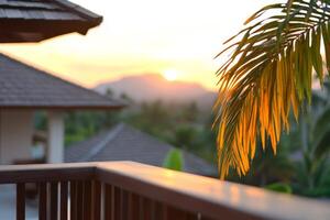 Sunset view from a balcony with palm leaves and mountains in the distance creating a tranquil atmosphere photo