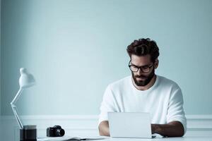 Young man with glasses working on laptop in modern workspace with camera and desk lamp photo