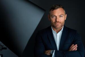 Man poses confidently in tailored suit against dark background with dramatic lighting technique highlighting his features photo