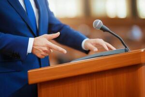 Speaker gestures passionately at a podium during a formal event in a well-lit hall with wooden accents photo