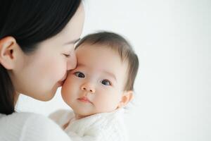 Mother lovingly kisses her baby during a quiet moment at home in a bright and serene setting photo