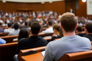 Group of students attending a lecture in a large auditorium during a university class in the afternoon photo