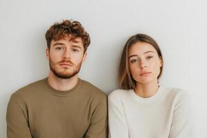 Young couple with serious expressions poses against a neutral backdrop in a modern, well-lit room photo