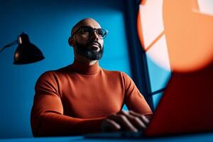 Professional man working late at night with laptop in modern workspace illuminated by unique lighting photo
