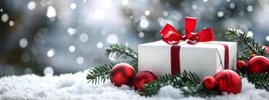 gift box wrapped with red ribbon and bow, surrounded by green pine branches and ornaments on soft snow, creating a festive winter setting photo