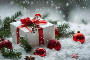 gift box with red ribbon and bow, resting on fresh snow, surrounded by green pine branches and red ornaments for a festive look photo