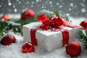 box with a red ribbon and bow, surrounded by green pine branches and red Christmas ornaments, resting on fresh snow for a festive holiday scene photo