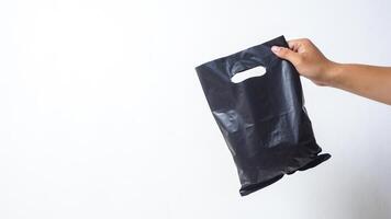 Hand Shows Black Blank Plastic Bag Mock Up with Handle on White Background photo
