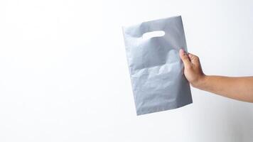 Hand Holding Empty Blank Gray Plastic Bag Mock Up on White Background photo