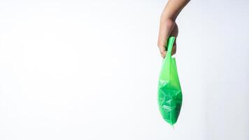 Side View of Hand Carrying Green Plastic Grocery Bag with Copy Space on White Background photo