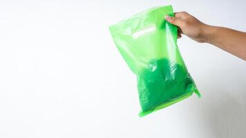 Hand Holding Filled Green Plastic Bag with Copy Space on White Background photo