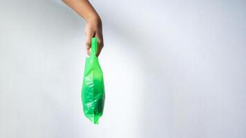 Side View of Hand Carrying Green Plastic Bag with Copy Space on White Background photo