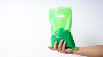 Hand Holding Green Disposable Plastic Bag with Handle on White Background photo