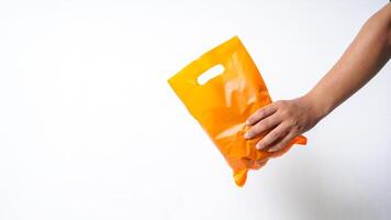 Hand Giving Orange Plastic Bag with Copy Space on White Background photo