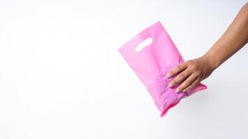 Hand Holding Filled Pink Plastic Bag Mock Up with Copy Space on White Background photo