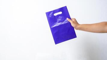 Hand Holding Purple Plastic Bag Mock Up with Copy Space on White Background photo