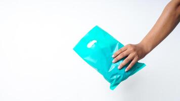 Hand Holding Turquoise Plastic Bag Mock Up with Copy Space on White Background photo
