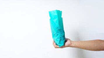 Side View of Hand Holding Filled Turquoise Plastic Bag on White Background photo