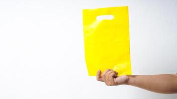 Hand Holding Blank Yellow Plastic Bag Mock Up on White Background photo
