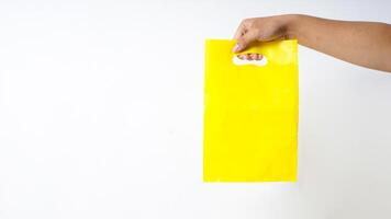 Hand Carrying Yellow Plastic Bag Mock Up on White Background photo