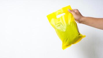 Hand Showing Yellow Plastic Mock Up Bag on White Background photo