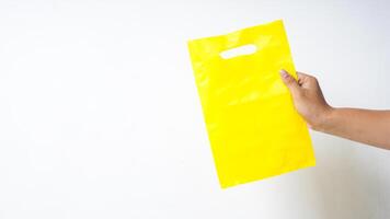 Hand Holding Yellow Plastic Bag Mock Up on White Background photo