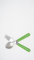 Rear view and copy space of modern stainless steel spoon and fork with green handle isolated on white background photo