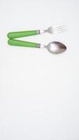 A pair of stylish stainless steel spoon and fork with green handle with copy space isolated on white background photo