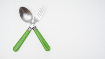 Top view of stainless steel spoon and fork with green handle isolated on white background photo