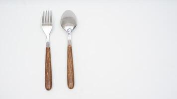 Rear view of stylish stainless steel spoon and fork with wooden handle isolated on white background photo