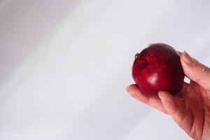 Hand presenting a red apple in a minimalist setting photo