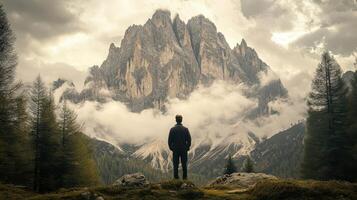 A man standing in front of a mountain with clouds in the background photo