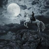 A man on a horse is riding in front of a full moon photo