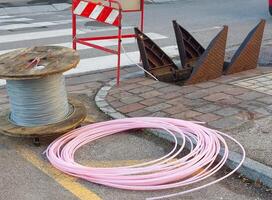 Laying fiber optic cable near an open manhole and a wooden spool photo